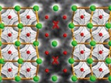 Two mirror-image domains (terbium in green, manganese in red, oxygen not shown) meet at a domain wal